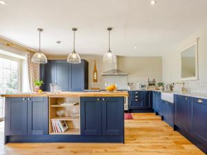 a kitchen with blue cabinets and wooden floors at The Stables in Cheddar +25 photos