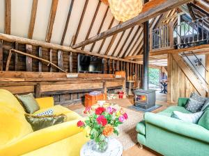 a living room with yellow couches and a fireplace at Old Shires Barn in Norton