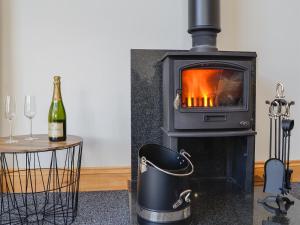 a wood stove with a bottle of wine next to a table at Holmegarth in Plumbland