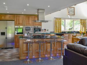 a kitchen with wooden cabinets and a island with bar stools at Holmegarth in Plumbland