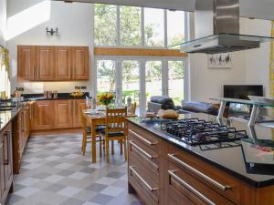 a kitchen with wooden cabinets and a stove top oven at Holmegarth in Plumbland