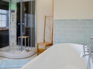 a bathroom with a bath tub and a shower at Holmegarth in Plumbland +9 photos