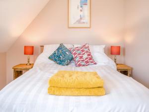 a bed with a yellow blanket on it with two lamps at The Old Stable At Henley View in Draycott +7 photos