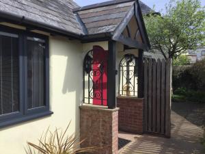 a house with a gate and a red window at The Bothy in Bradworthy +9 photos