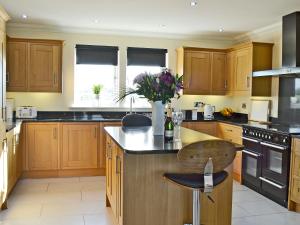 a kitchen with wooden cabinets and a vase of flowers at Wheatfield House in Kilmaurs +27 photos