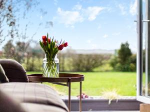 a vase of flowers on a table in front of a window at Longridge in Peldon