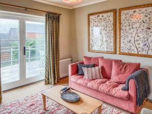 a living room with a pink couch and a table at Cairn Ryan in Saint Mawes