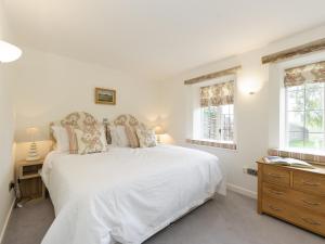 a white bedroom with a bed and two windows at The Row in Much Marcle