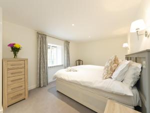 a bedroom with a white bed with a dresser and a window at The Row in Much Marcle