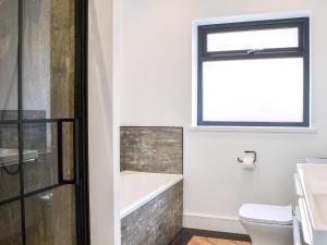 a bathroom with a tub and a toilet and a window at Linden Manor in Bridlington
