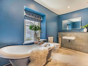 a blue bathroom with a white tub and a toilet at Millgate Fosse Cottage in Richmond