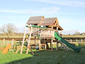 a wooden playground with a house and a slide at Bwthyn Onnen-Oa5 in Ystrad Meurig