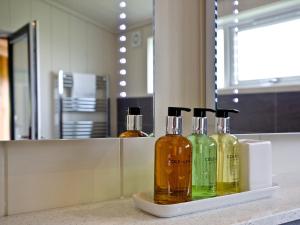 three bottles of alcohol sitting on a counter in a bathroom at Willow Lodge in Hassocks