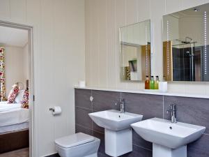 a bathroom with two sinks and a toilet and a mirror at Willow Lodge in Hassocks