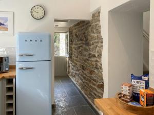 a refrigerator in a kitchen with a stone wall at Barn Cottage in Saint Mawgan