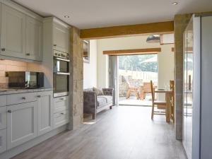 a kitchen with white cabinets and a living room at Deer Park - Uk33360 in Reeth