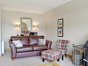 a living room with a leather couch and a chair at Lochnagar Lodge in Aviemore