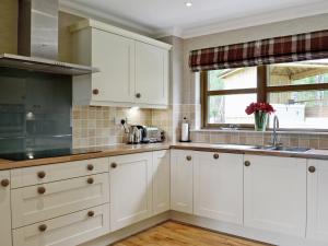 a kitchen with white cabinets and a window at Lochnagar Lodge in Aviemore