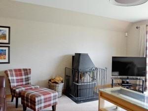a living room with a fireplace and a tv at Lochnagar Lodge in Aviemore +8 photos
