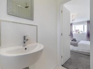 a white bathroom with a sink and a bedroom at The Old School House in Barnsley