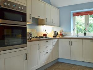 a kitchen with white cabinets and a stove top oven at Rose Cottage in Rillington