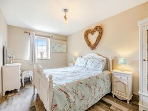 a bedroom with a bed with a heart hung on the wall at The Old Stables in Cumberworth