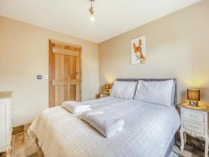 a bedroom with a large bed with white sheets at The Old Stables in Cumberworth