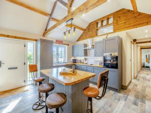a kitchen with a large island with bar stools at The Old Stables in Cumberworth +17 photos