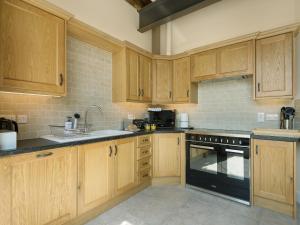 a kitchen with wooden cabinets and a black appliance at Church View - Ukc2302 in Wainfleet All Saints