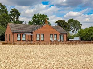 a red brick house in a field of wheat at Highgrove in Gissing