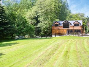 a large grass field with a wooden house at Foxton Barn - Uk47297 in Harrietsham