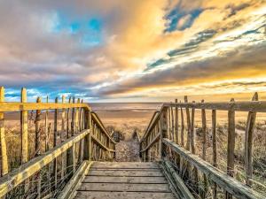a wooden bridge leading to the beach with a sunset at The Pastures - Uk41853 in Maltby le Marsh