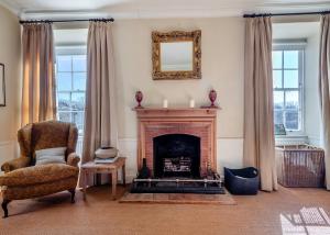 a living room with a fireplace and a chair and a mirror at Oxnead Hall in Brampton