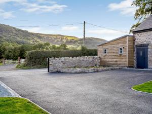 a house with a stone wall next to a garage at Cor Tarw - Uk12743 in Acrefair
