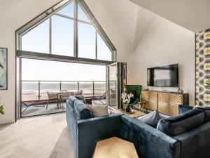 a living room with a blue couch and a large window at Sandbanks in Bridlington