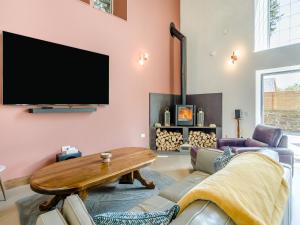a living room with a couch and a tv on the wall at Auld Kirk House in Duns