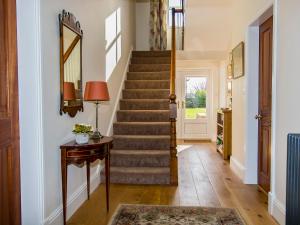 a hallway with stairs and a table and a mirror at The Laburnums in Askham