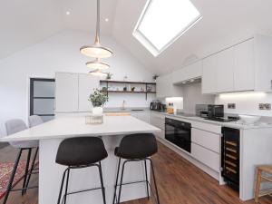 a kitchen with white cabinets and a large island with bar stools at Bimblebox Stable in Reepham