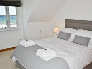 a bedroom with a white bed with towels on it at Gylly Beach View - Tor in Falmouth