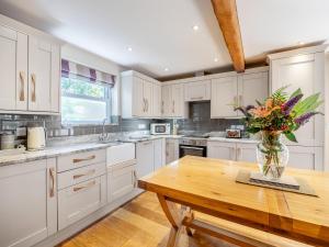 a kitchen with white cabinets and a vase of flowers on a table at The Rose- Uk47155 in Burgh le Marsh