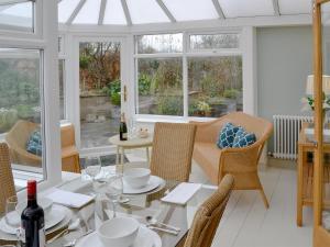 a dining room with a table and chairs and windows at May Cottage in Bacton