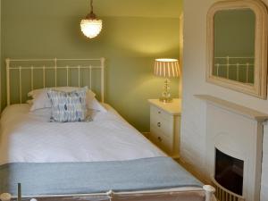 a bedroom with a bed with a fireplace and a mirror at May Cottage in Bacton