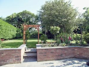 a garden with an arch and a brick wall at May Cottage in Bacton