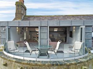 a patio with chairs and a glass table on a house at Cragdale Penthouse in Settle