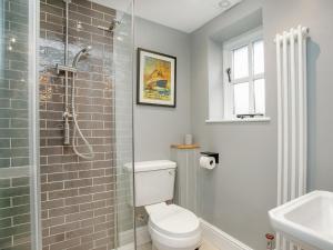 a bathroom with a toilet and a glass shower at Wheelwright Cottages in Branscombe