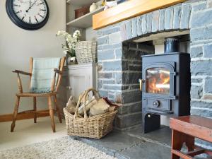 a living room with a stone fireplace with a stove at Maes Y Bryn Farmhouse in Llanwrda