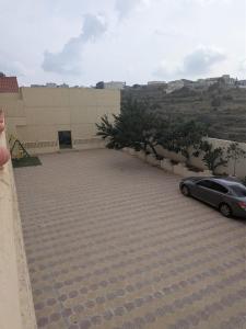 a woman standing next to a car in a parking lot at شقق ضوء القمر Moonlight Apartment in Rahwat al Barr