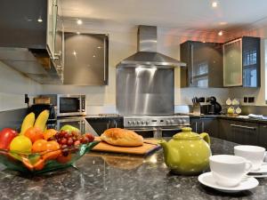 a kitchen with a counter with a bowl of fruit at Oswald House in Llansantffraid