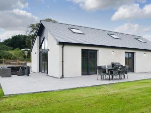 a white house with a patio with a table and chairs at The Byre in Castle Douglas