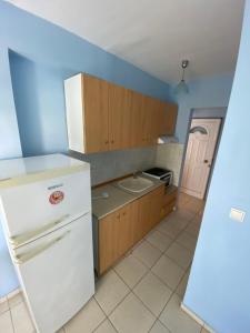 a kitchen with a white refrigerator and wooden cabinets at Nelli rooms in Polychrono